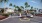 a entrance to a apartment complex with palm trees and cars
