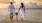 a man and woman holding hands with a little girl on a beach